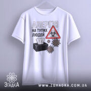 Футболка алергія люди. Біла футболка з коротким рукавом, підвішена на вішалці. На фоні світло-сірий градієнт. Принт містить текст 'АЛЕРГІЯ НА ТУПИХ ЛЮДЕЙ', символ небезпеки та малюнки мікробів.