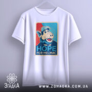 Футболка Альф білого кольору, підвішена на вішалці, ракурс спереду, фон світло-сірий, принт з персонажем свині в кепці, текст "HOPE FOR MELMAC" на кольоровому фоні.