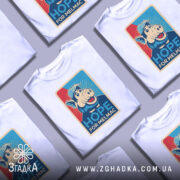 Футболка Альф білого кольору, зображена на манекені, ракурс спереду, фон світло-сірий, принт з веселим персонажем свині в кепці, текст "HOPE FOR MELMAC" на яскравому фоні.