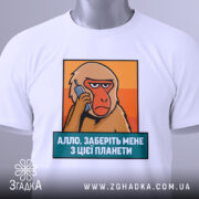 Футболка Алло заберіть мене. Біла футболка, складена на поверхні, з принтом мавпи, що тримає телефон. Текст під принтом синій, на фоні оранжевих відтінків. На комірці видно етикетку.