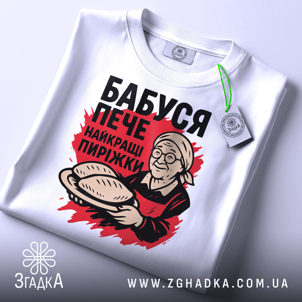 Футболка бабуся пече пиріжки, біла, зображена зверху, фон світло-сірий, принт з бабусею, що тримає пиріжки, з етикеткою на рукаві.