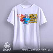 Футболка бабуся супергерой, біла, підвішена на вішалці, фон світло-сірий, принт з бабусею-супергероєм у синьому костюмі з червоним плащем, що біжить, з написом 'Бабуся завжди прийде на допомогу'.