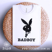 Футболка badboy кролик білого кольору, зображена зверху на плетеній кошику, фон білий, принт чорного кольору з силуетом кролика та написом 'BADBOY' під ним.