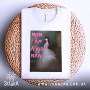 Футболка багата незалежна, білого кольору, зображена на плетеній кошику, фон світлий, принт з написом 'MOM, I AM A RICH MAN' у рожевих літерах на фоні зображення жінки в білій сукні.