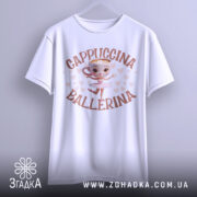 Футболка Ballerina Cappuccino білого кольору, підвішена на вішалці, з фронтального ракурсу. Принт з малюнком балерини, що танцює, з чашкою капучино замість голови, оточено сердечками. Фон світло-сірий.