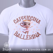 Футболка Ballerina Cappuccino білого кольору, складена на поверхні, з видимим етикеткою. Принт з малюнком балерини в центрі, оточено сердечками. Фон світло-сірий.