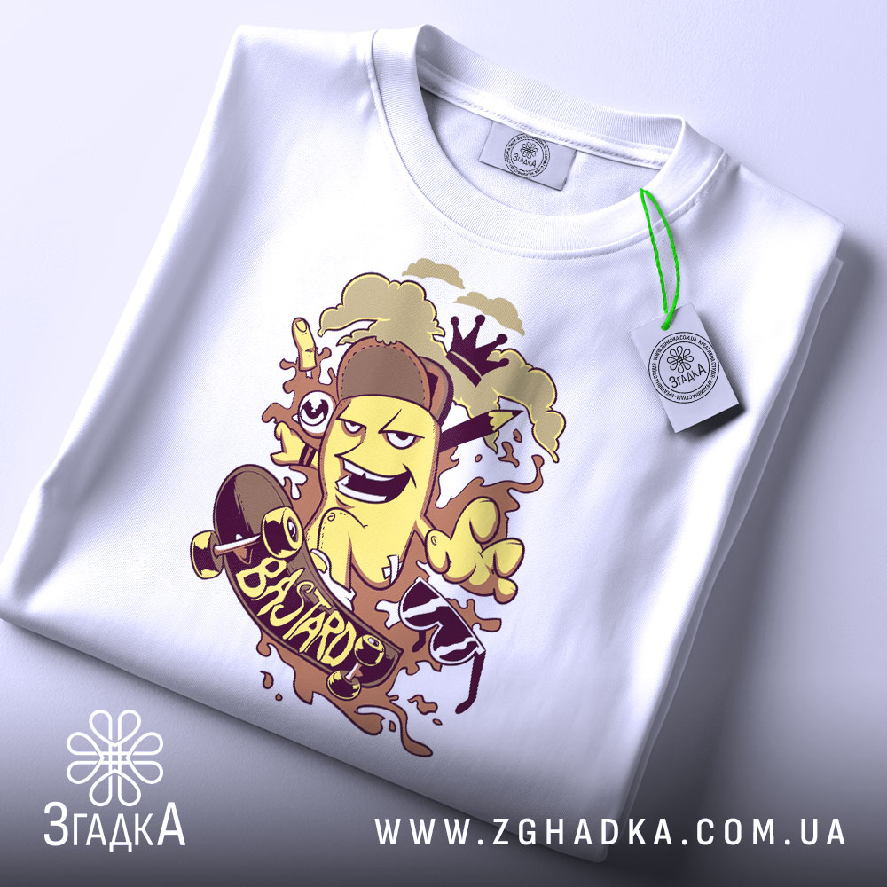 Футболка банан скейтер білого кольору, зображена зверху, на столі, фон світло-сірий, принт з жовтим бананом у шапці, що катається на скейтборді, з веселими елементами, на футболці є етикетка з зеленим шнурком.