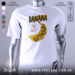 Футболка банан тату білого кольору, зображена на манекені, ракурс спереду, фон світло-сірий, принт з жовтою бананою та чорними написами, деталі принта включають малюнки черепів та інших елементів.