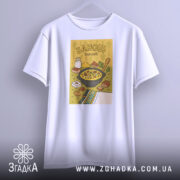 Футболка банош українська кухня, біла, підвішена на вішалці, фон світло-сірий, принт з жовтим фоном, на якому зображена каструля з баношем, молоко, хліб та інші інгредієнти.