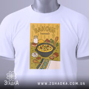 Футболка банош українська кухня, біла, складена на столі, фон світло-сірий, принт з жовтим фоном, на якому зображена каструля з баношем, молоко, хліб та інші інгредієнти, з зеленим ярликом.