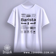 Футболка бариста стиль, біла, підвішена на вішалці, фон світло-сірий, принт чорного кольору з текстом та іконками, що описують інгредієнти для приготування кави.