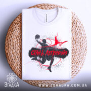 Футболка баскетбол стань легендою, біла футболка складена на плетеній основі, принт з баскетболістом у чорному та червоному кольорах, фон натуральний, акцент на текстурі основи.