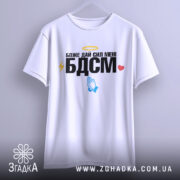 Футболка БДСМ білого кольору, зображена на вішалці, фон світло-сірий, принт містить текст "Боже дай сил мені БДСМ" з жовтим німбом, блискавкою, блакитними руками та червоним сердечком.