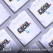 Футболка БДСМ білого кольору, зображена на манекені, фон світло-сірий, принт містить текст "Боже дай сил мені БДСМ" з жовтим німбом, блискавкою, блакитними руками та червоним сердечком.