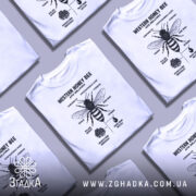 Футболка бджола принт білого кольору, зображена на манекені, фон світло-сірий, принт чорного кольору з детальним зображенням бджоли та текстом.