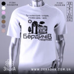 Футболка Бердичів надихає. Біла футболка з коротким рукавом, зображена на манекені, фон нейтральний. Принт містить текст і графічні елементи, що зображують архітектурні деталі та природу.