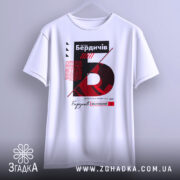 Футболка Бердичів заснований, біла, підвішена на вішалці, фон світлий, принт з червоним та чорним текстом, графічні елементи.