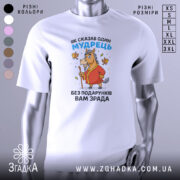 Футболка без подарунків зрада. Білий колір, зображена спереду на манекені, фон світло-сірий. Принт з мультяшним конем у червоному халаті, що тримає палицю, з пташками навколо.