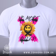 Футболка без правил, біла, складена на поверхні, фон світлий, принт з соняшником, усміхненим обличчям та написом 'NO MORE RULES!' у яскравих кольорах, з етикеткою на комірці.