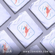 Футболка біжу волосся позаду, біла, зображена на манекені, фон світлий, принт з рожевим персонажем, що біжить, з короною та блакитним волоссям, оточений зірочками та лініями.