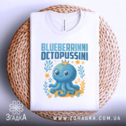 Футболка Blueberrinni Octopussini білого кольору, зображена в складеному вигляді на плетеній основі. Принт з восьминогом, оточеним рослинами та квітами, з короною на голові, видима етикетка на комірці.