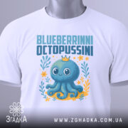 Футболка Blueberrinni Octopussini білого кольору, зображена в складеному вигляді на білому фоні. Принт з восьминогом, оточеним квітами та рослинами, з короною на голові, з етикеткою на комірці.