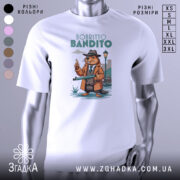 Футболка Bobritto Bandito білого кольору, зображена на манекені з правого боку, фон світло-сірий, принт з ведмедем у капелюсі та пальто, що тримає гвинтівку, на фоні вуличного ліхтаря та будинків.