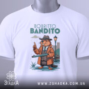 Футболка Bobritto Bandito білого кольору, складена на поверхні, фон світло-сірий, принт з ведмедем у капелюсі та пальто, що тримає гвинтівку, з етикеткою на зеленому шнурку.