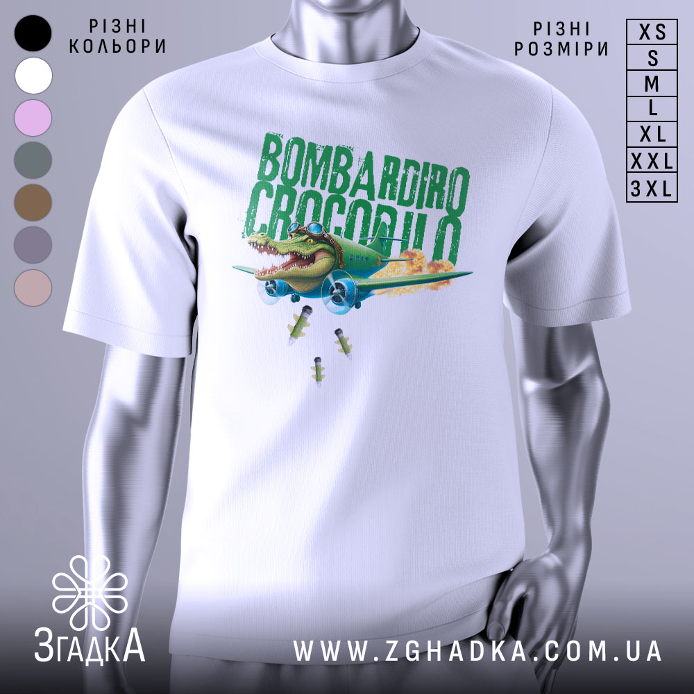 Футболка Bombardiro Crocodilo білого кольору, зображена на манекені з правого боку, фон світло-сірий, принт з крокодилом в пілотських окулярах, що сидить в літаку, з зеленим текстом 'BOMBARDIRO CROCODILO' та деталями бомб, що падають.