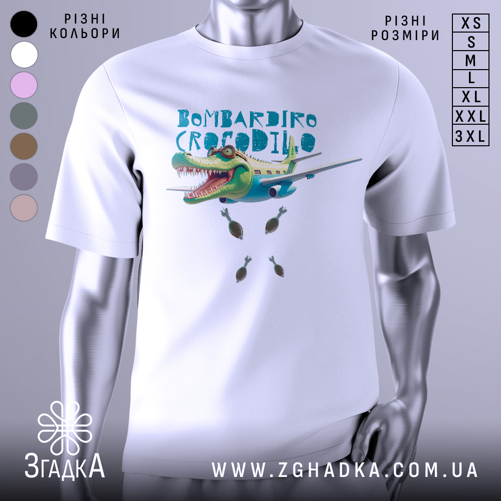 Футболка Бомбардіро Крокоділо білого кольору, зображена з фронтального ракурсу на манекені, фон нейтральний, принт з крокодилом, що літає на літаку, з бомбами під ним.