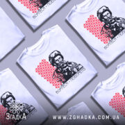 Футболка борітеся поборете, білого кольору, зображена на манекені з ближнього ракурсу, фон світло-сірий, принт з червоним орнаментом та чорно-білим зображенням чоловіка в військовій формі.