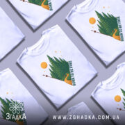 Футболка born free білого кольору, зображена на манекені, з принтом лісу, дороги та сонця, ракурс спереду, фон світло-сірий.