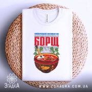 Футболка борщ подарунок, біла, складена на кошику з плетеного матеріалу, фон світлий, принт з червоною написом 'БОРЩ' та малюнком тарілки з борщем.