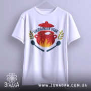 Футболка борщ український вайб, біла, підвішена на вішалці, фон світло-сірий, принт з червоним горщиком, вогнем, написом 'UKRAINIAN VIBE' та зеленими гілками.