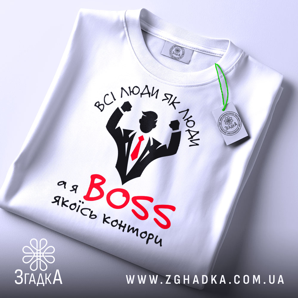 Футболка бос контори білого кольору, зображена зверху, складена на поверхні, фон світлий, принт з чорним силуетом чоловіка в костюмі з червоною краваткою та написом "ВСІ ЛЮДИ ЯК ЛЮДИ, а я BOSS якоїсь контори", на футболці є етикетка.