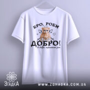 Футболка бро роби добро, біла, підвішена на вішалці, фон світлий, принт з ведмедиком у короні, напис 'ДОБРО!' з елементами сердець і стріл.