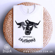 Футболка брутальна скотиняка, білого кольору, зображена зверху на плоскій поверхні з плетеним елементом, фон світлий, принт чорного кольору з графічним зображенням голови корови та написом 'Брутальна скотиняка'.