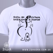 Футболка будь як дупця, білого кольору, складена на поверхні, фон світло-сірий, принт чорного кольору з малюнком кота ззаду та текстом, на комірці зелена етикетка.