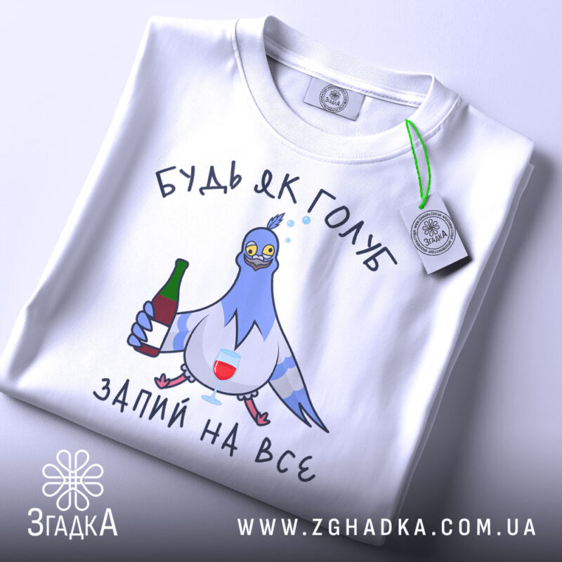 Футболка будь як голуб, білого кольору, зображена зверху, на ній видно принт з голубом, який тримає пляшку та келих, текст "ЗАПИЙ НА ВСЕ", на комірці є етикетка з зеленим шнурком.