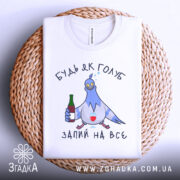 Футболка будь як голуб, білого кольору, зображена зверху на плетеній основі, принт з голубом, який тримає пляшку та келих, текст "ЗАПИЙ НА ВСЕ".