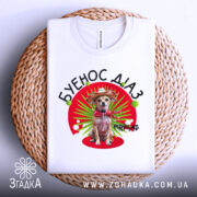 Футболка буенос діаз білого кольору, зображена на плетеній основі, фон світлий, принт з собакою в капелюсі та червоному шарфі на зеленому фоні з червоним колом.