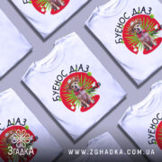 Футболка буенос діаз білого кольору, зображена на манекені, фон світлий, принт з собакою в капелюсі та червоному шарфі на зеленому фоні з червоним колом.