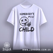 Футболка бунтівна дитина, біла, зображена на вішалці, фон світлий, принт з смайлом, рукою з черепом та текстом 'SOMEBODY'S Feral CHILD' у чорному кольорі, видно деталі крою.