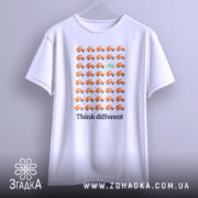 Футболка бути іншим. Біла футболка, підвішена на вішалці, з принтом оранжевих автомобілів і зеленим велосипедом. Фон нейтральний, а ракурс зосереджений на футболці.