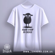 Футболка бути іншим. Біла футболка, підвішена на вішалці, з принтом чорної овечки, зображено спереду. Принт виконаний у чорно-білих тонах, текст "BLACK SHEEP BY CHOICE" розташований під овечкою. Фон світлий, що підкреслює футболку.