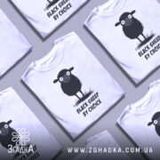 Футболка бути іншим. Біла футболка з принтом чорної овечки, зображено спереду, на фоні світлого градієнта. Принт виконаний у чорно-білих тонах, текст "BLACK SHEEP BY CHOICE" розташований під овечкою. Рукава футболки короткі, тканина виглядає м'якою.