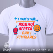 Футболка бий і усміхайся. Біла футболка на манекені, з кольоровим принтом на грудях, що містить текст та малюнки. Фон світло-сірий.