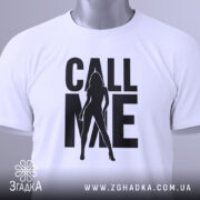 Футболка call me білого кольору, складена на столі, фон світло-сірий, принт чорного кольору з силуетом жінки та написом 'CALL ME', на комірці видна етикетка.