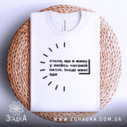 Футболка часова петля, біла, складена на плетеній основі, фон білий, принт чорного кольору з текстом.