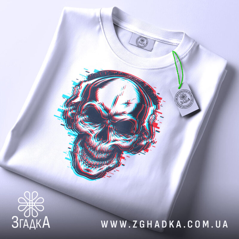 Футболка череп в навушниках, біла, складена на поверхні, фон світло-сірий, принт черепа з навушниками в стилі 3D, з етикеткою на зеленому шнурку.